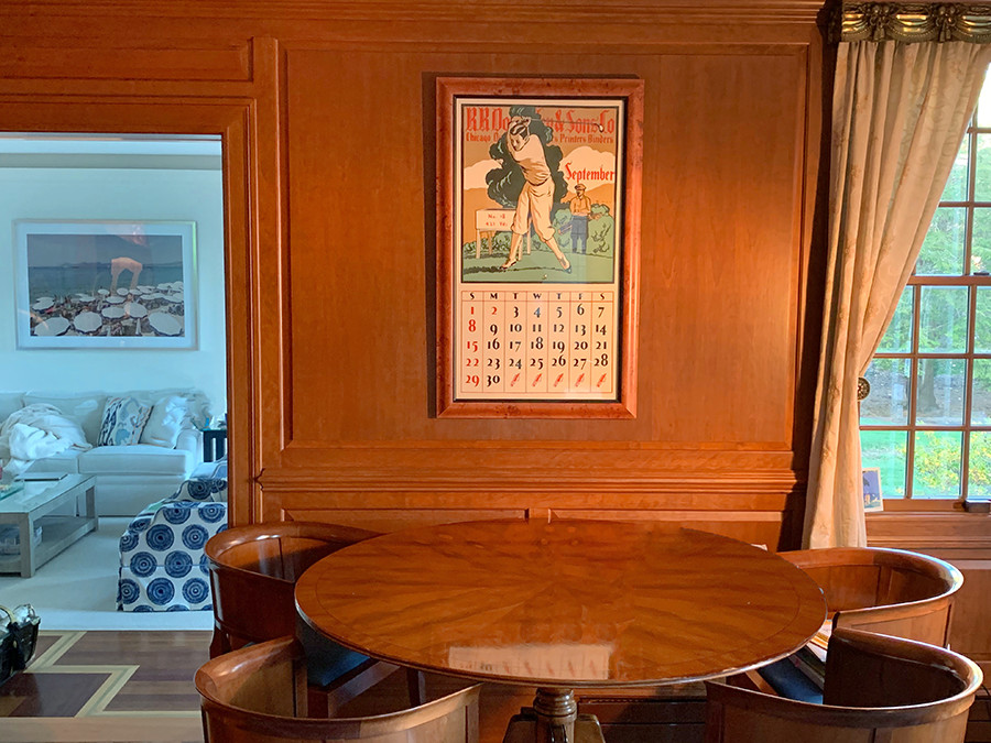 wood furnished room, framed golfer calendar, small view of side room; brown, green, white, blue