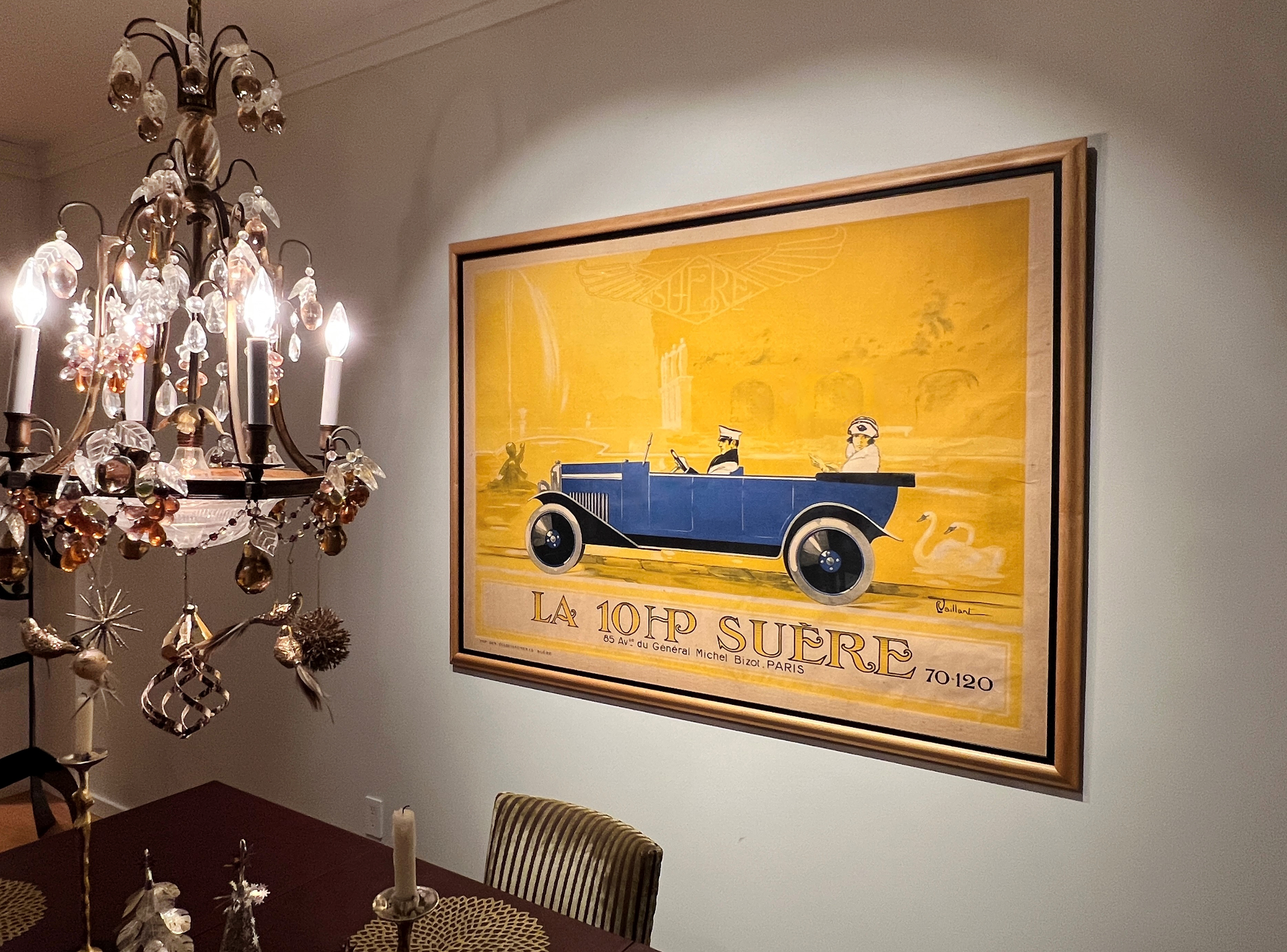 yellow poster with blue car, chandelier with ornaments, dining room table